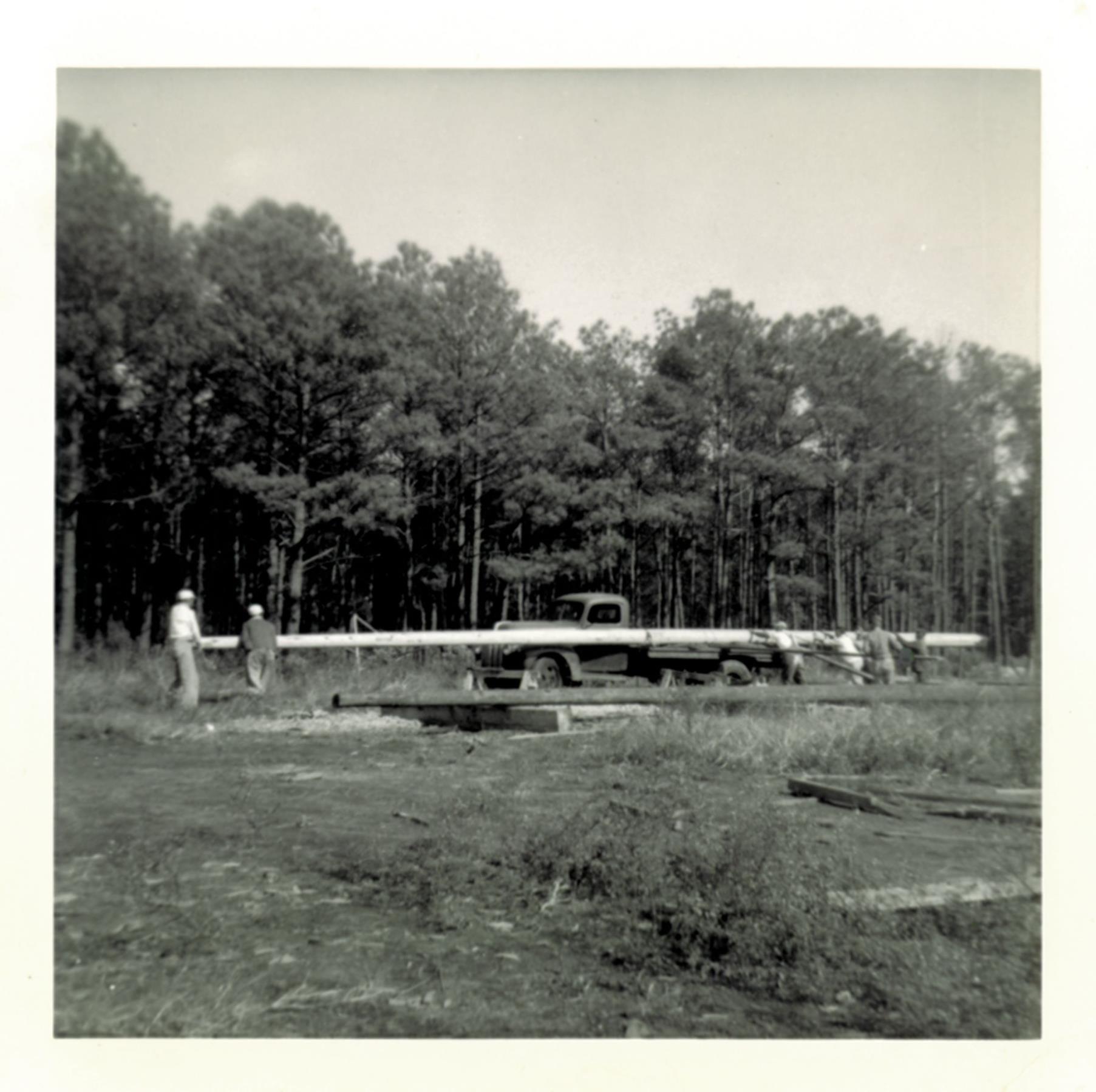 Timber for boat mast transported through the yard. Undated.