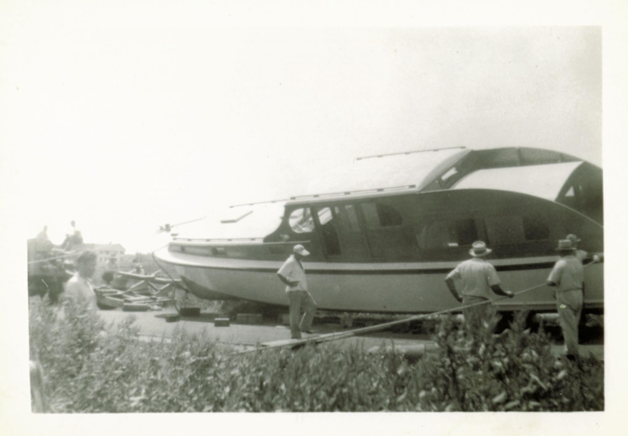 Neighbors gathered to watch and help launch a yacht into the ditch. 15 October 1955.