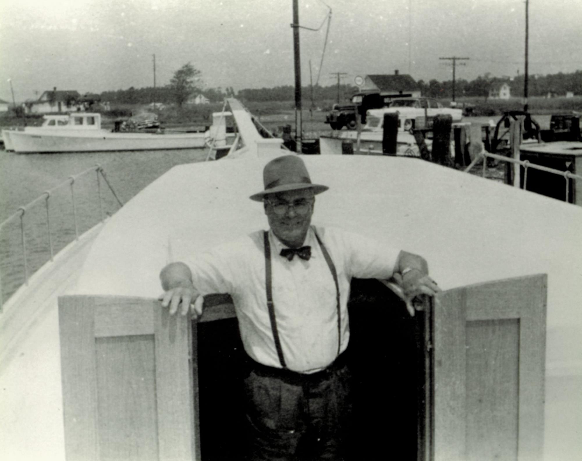Bronza Parks standing in the cockpit of the skipjack yacht Barbara Batchelder at the Wingate waterfront. Probably autumn 1955 or spring 1956.