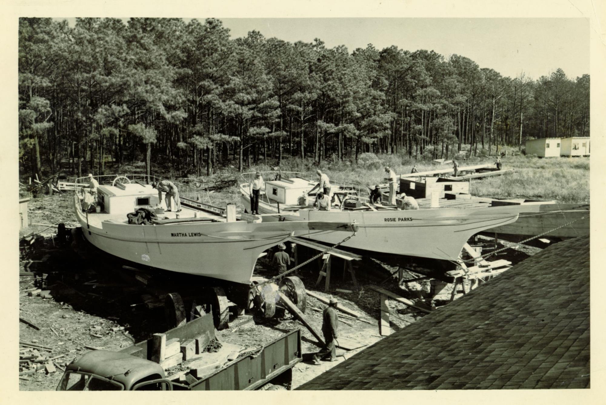 Photo of Bronza Parks' boatyard taken from roof of the boat shed. Woods are north of the yard. Firehouse out of view to the left, residence out of view to the right. Skipjacks left to right: Martha Lewis , Rosie Parks, Lady Katie. Undated, about October 1955.