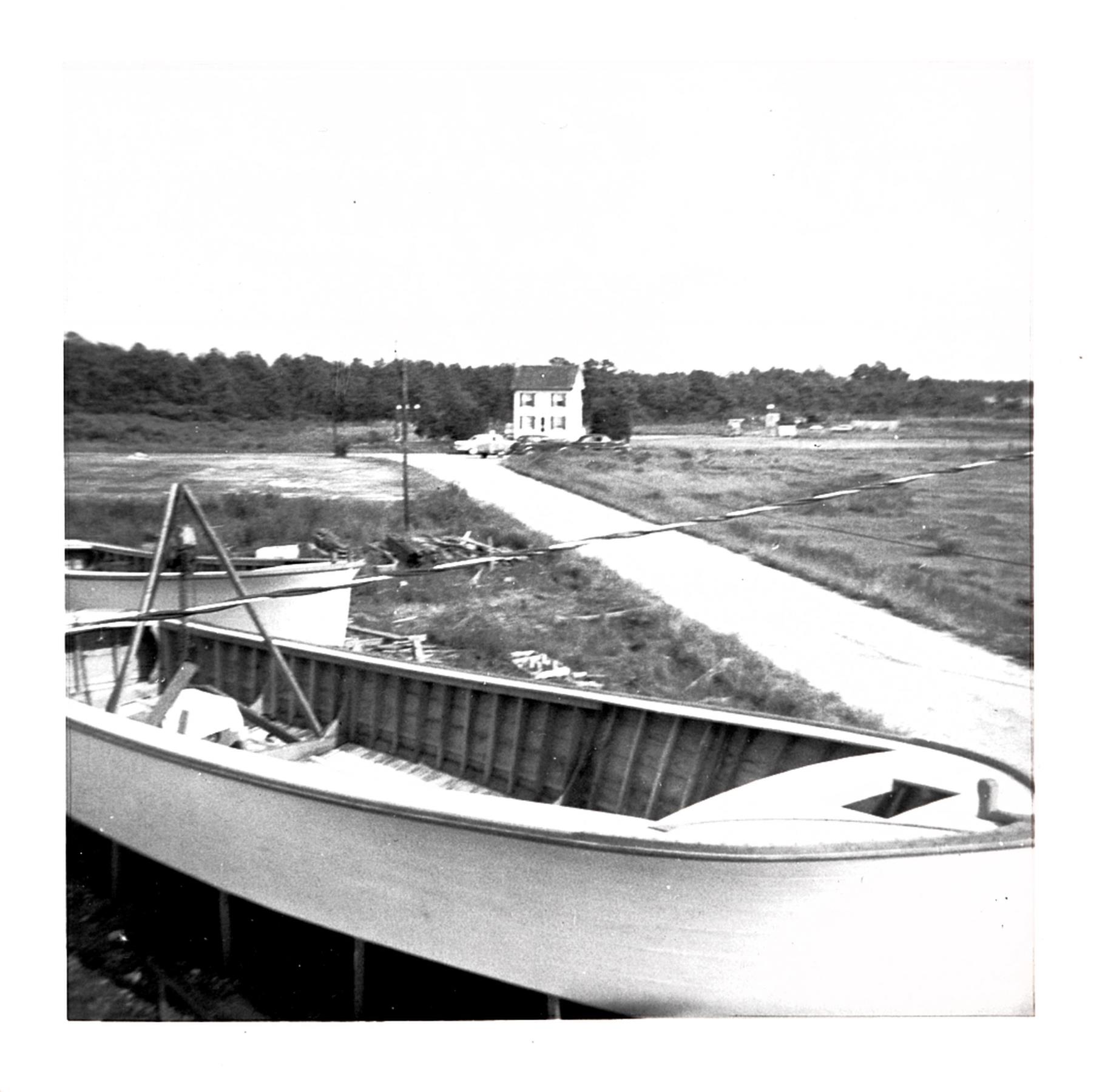 Deadrise workboat hull in Bronza's boatyard. Ridon Powley's house in background. August 1955.