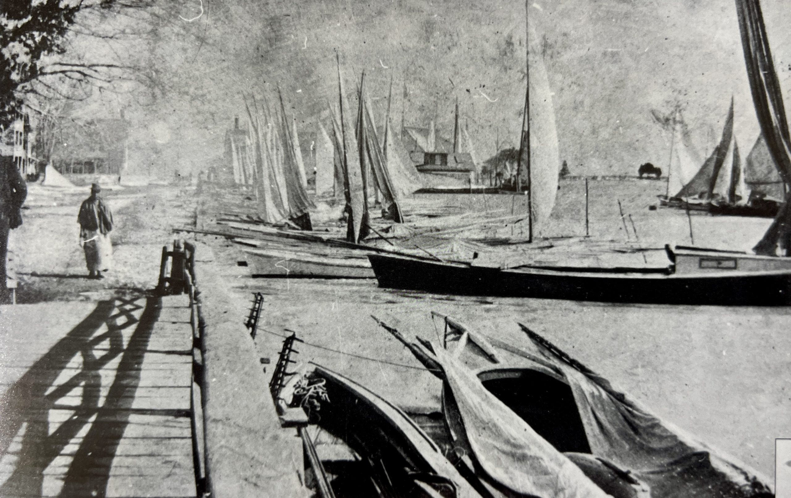 A cabin skiff moored with other oyster tonging boats in St. Michaels harbor. A culling board is laid across the deck, and handles of oyster tongs extend from the stern. Photo: M. D. B. Bielaski, ca. 1890. Courtesy Chesapeake Bay Maritime Museum. Catalog #: 0000.0531.0001.00 Object Name : negatives Title : FOOTBRIDGE - LOOKING TO NAVY POINT, WITH MANY SAIL Artist-Maker : Bielaski, M D B Photographer Date Made : Range,Circ 01/01/1890 - 12/31/1890 Description : FOOTBRIDGE - LOOKING TO NAVY POINT, WITH MANY SAILING SKIFFS, MAN AND WOMAN CROSSING FOOTBRIDGE FOOT OF CHERRY STREET